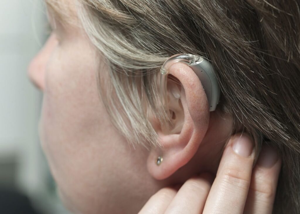 A woman wearing a hearing aid, showing the kind of care you find at hearing aids centers near me.